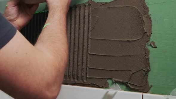 Applying Tile Adhesive to the Bathroom Wall By the Hands of an Unrecognizable Person Slow Motion