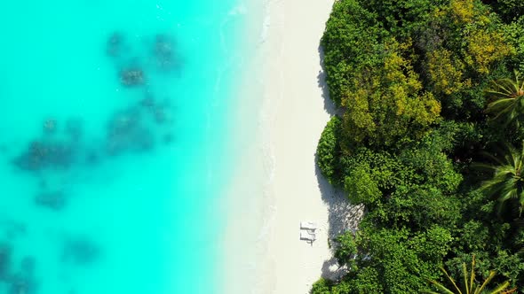 Daytime fly over travel shot of a white sand paradise beach and turquoise sea background 