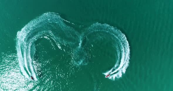 Aerial: Two Water Bikes Jet Ski Are Draw a Heart Shape on the Water on the Sea.