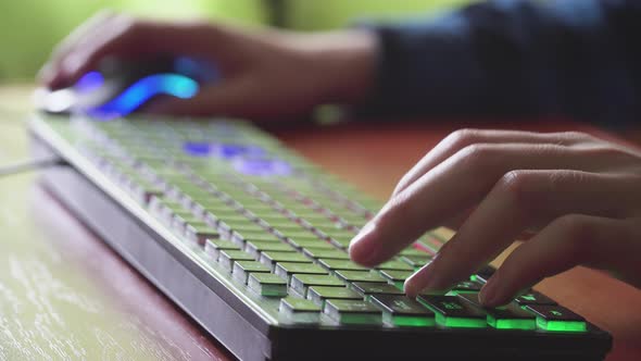 Young Gamer Plays a Video Game Uses Gaming Illuminated Keyboard