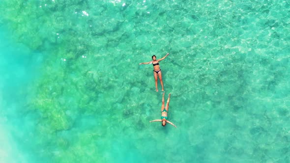 Ladies happy and smiling on relaxing resort beach break by shallow ocean and white sand background o