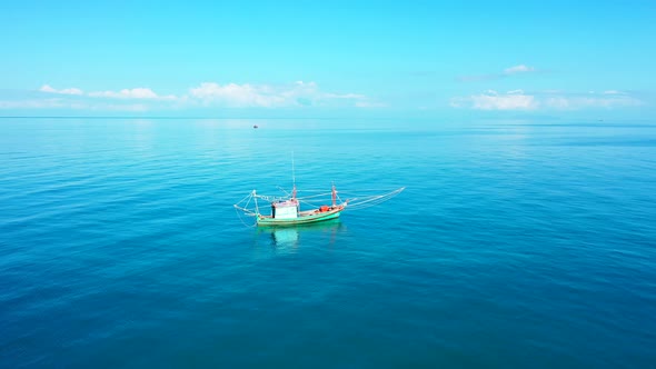 Fishing boat with overhanging nets floating on calm clear water of azure lagoon on a sunny summer da