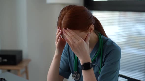 Closeup Face of Exhausted Tired Young Female Doctor in Blue Green Medical Uniform Massaging Temples