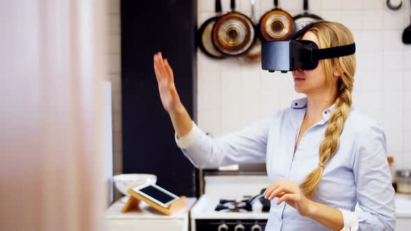 Woman using virtual reality headset in kitchen
