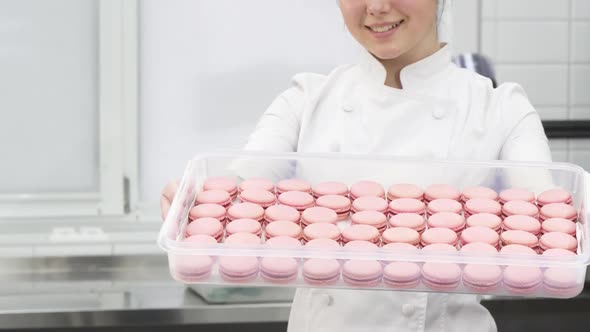 Cropped Shot of a Pastry Chef Smiling Holding out Tray with Pink Macaroons