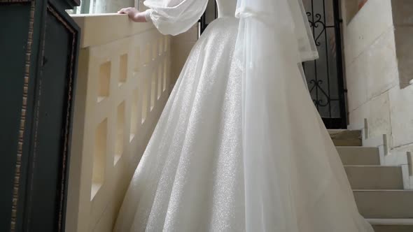 A Beautiful Bride in a Wedding Dress Stands on the Steps