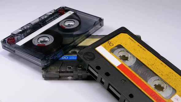 Three Vintage Audio Cassettes Rotate on White Background