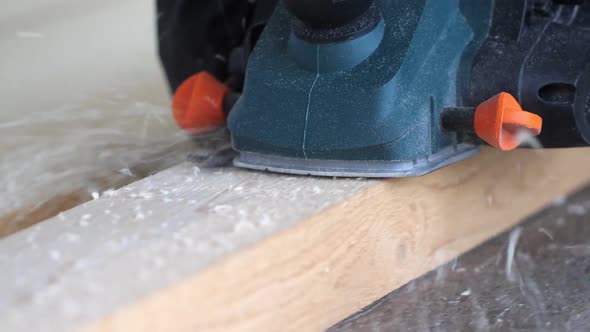 Man Shaving Wooden Plank with Electrical Hand Planer