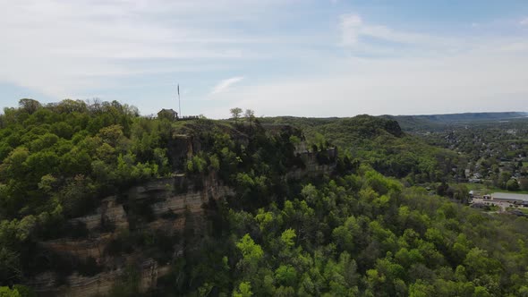 Panoramic view of outcropping of mountain with shelter, flag, fencing along walking to point.