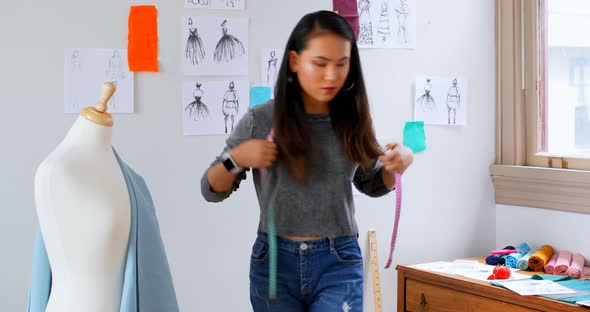 Fashion designer looking at sketch and measuring the fabric