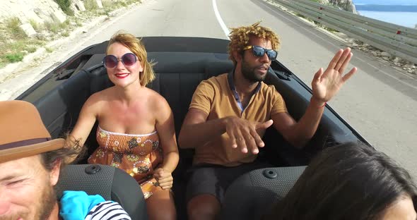 Beautiful blonde woman and handsome black man riding in the back of convertible