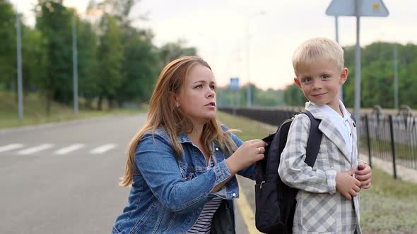 Closeup of a Caring Mother Adjusts the Backpack on His Back Before School