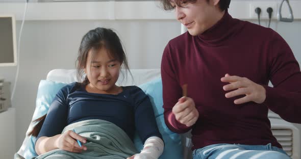 Asian Man Visiting Sick Teen Sister in Hospital and Painting Together