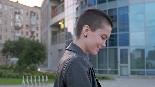 Young Woman with Shaved Hair Walking Against Urban Background