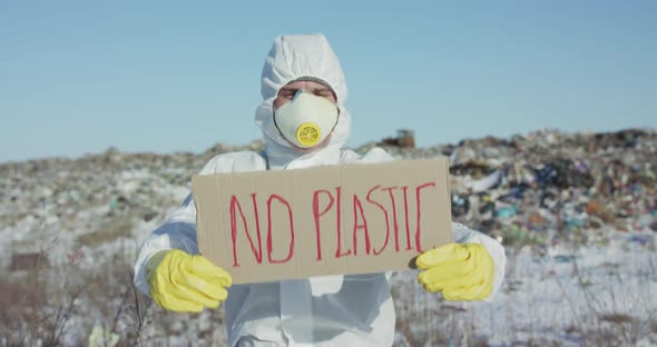Portrait of Man Wore in Protective Suit Show Protest Sign "No Plastic" at Camera
