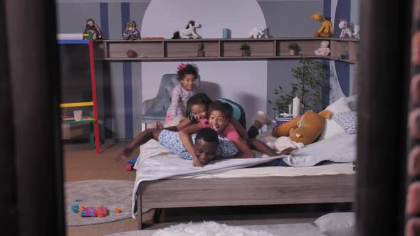 Black Dad with Daughters Making Family Heap on Bed
