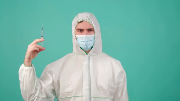Man in Protective Suit Medical Mask and Goggles Staying Holding a Syringe with Vaccine