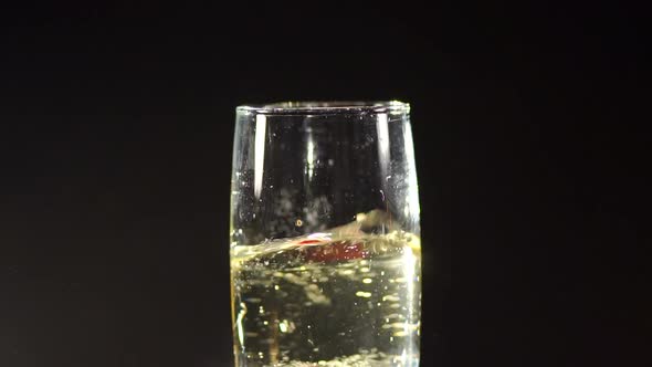 Strawberry Falling in a Glass of Champagne in Dark