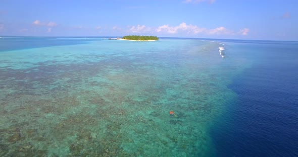 Aerial drone view of a man and woman couple snorkeling over the coral reef of a tropical island