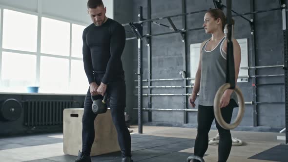 Coach Demonstrating Woman How to Lift Kettlebell