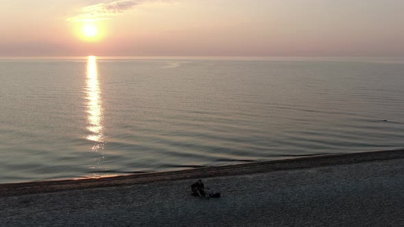 Man playing the guitar on the beach at sunset - aerial view