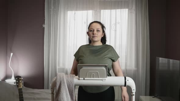 Portrait of young motivated woman walking on treadmill for weight loss 