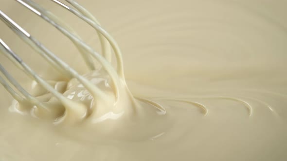 Stirring melted liquid white chocolate with steel whisk. Cooking chocolate dessert