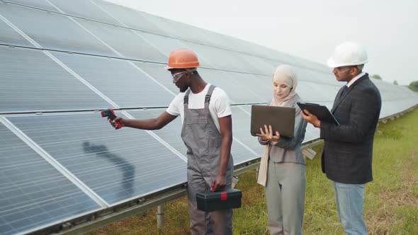 Muslim Woman and Indian Man Standing with African Technician and Checking