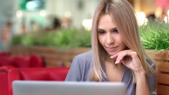 Portrait of Happy Beautiful European Woman Enthusiastically Looking at Screen Using Laptop