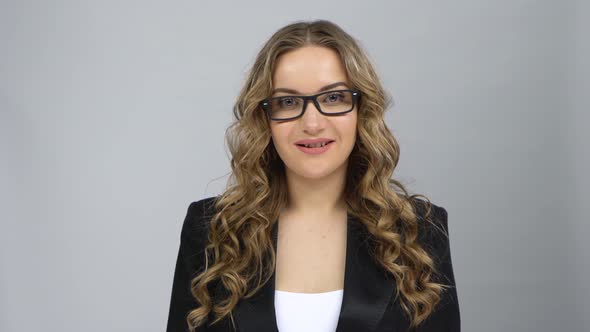 Portrait of Girl in Bussines Suit Fixing Her Glasses and Raising Eyebrow Looking at Camera