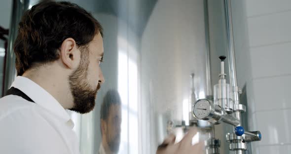 Beer Production. Brewery Worker Checking Beverage Equipment at Brewery or Beer Plant. Close Up