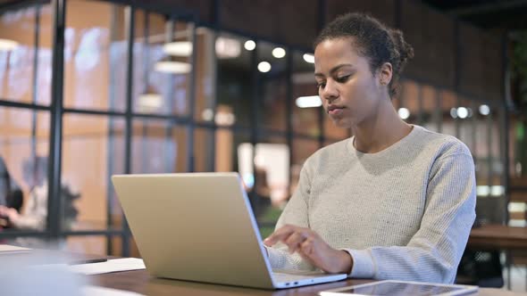 African Woman Leaving Office After Working on Laptop