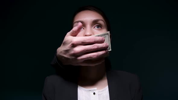 Money buys silence. Someone is covering a woman's mouth with dollars