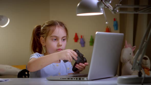 Happy Little Girl Having Fun in a Video Game with a Joystick at Home