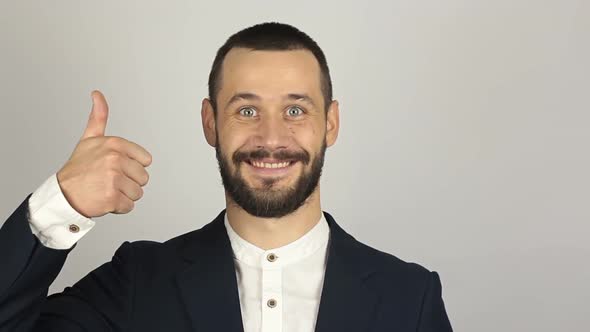 Young Handsome Businessman Is Smiling and Showing Thumb Up with Two Hands