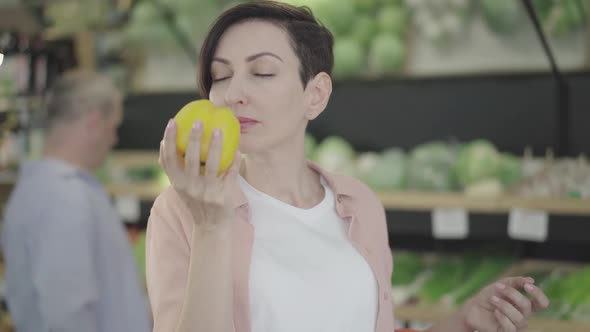 Portrait of Beautiful Woman Smelling Organic Yellow Bell Pepper and Smiling. Positive Young