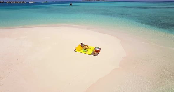 Aerial drone view of a man and woman couple having a picnic meal on a tropical island beach