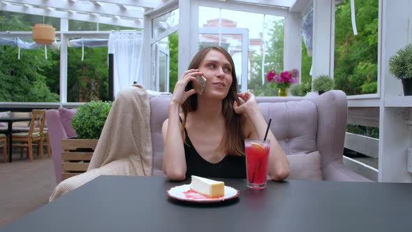 Woman Sitting In Outdoor Restaurant Talking Mobile Phone