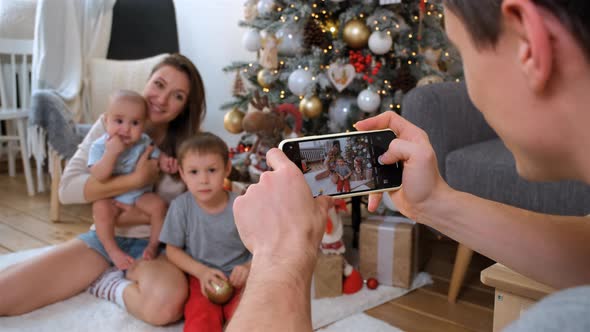 Father Making Family Photos By Phone at Christmas