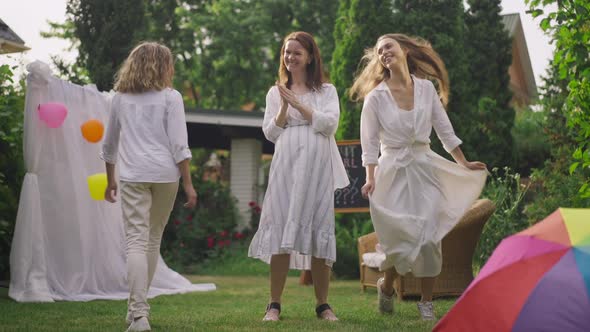 Pleased Relaxed Pregnant Woman Standing on Backyard As Teenage Girl and Young Woman Dancing Walking