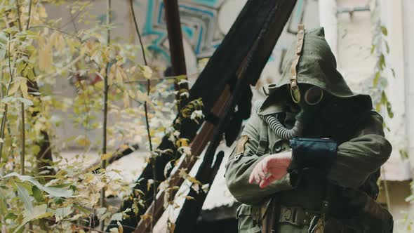 Scientist in Protective Suit Looking at the Device in His Hand