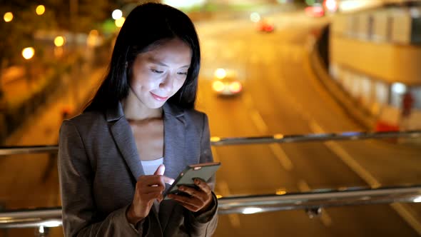 Business woman using smart phone in city at night 