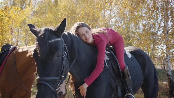 Young Caucasian Female Equestrian Lying on Horseback and Caressing Her Pet