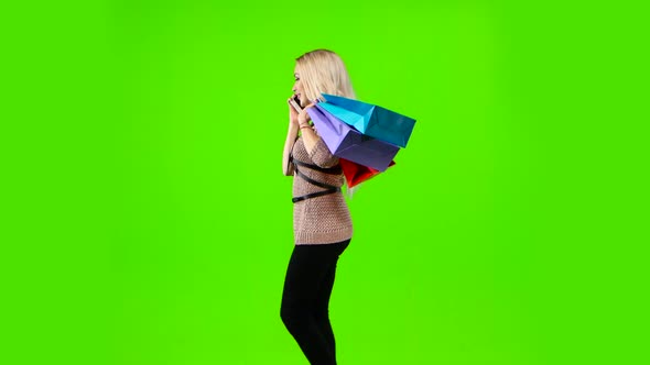 Girl with Curly Hair with Bags in Their Hands on the Phone. Green Screen. Side View