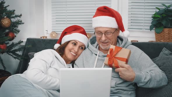 A Happy Middleaged Couple with Santa Hats Congratulate Their Relatives and Friends Via Video Link on