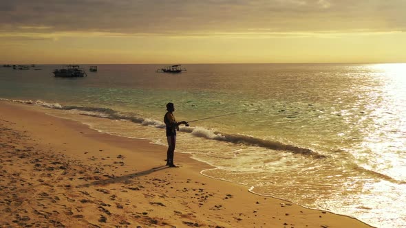 Male model fishing alone on perfect sea view beach lifestyle by blue green sea with white sand backg