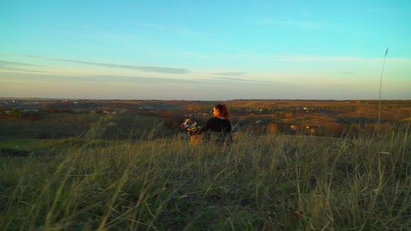 Young Girl and American Staffordshire Terrier Sitting in Meadow at Sunset