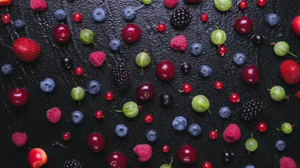 Fresh wild berries on black wooden background, top view