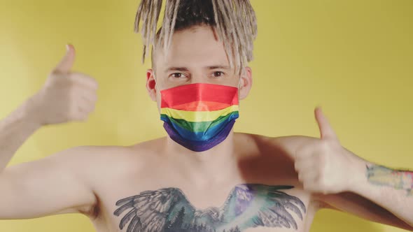 Naked handsome young man in LGBT mask showing gesture of like.