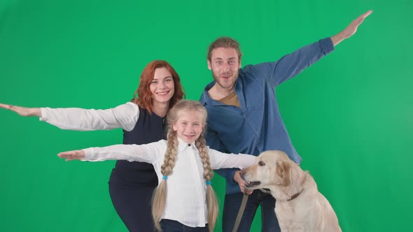 Loving Parents with a Female Child and a Labrador Dog Cheerfully Show a Flying Plane on a Green